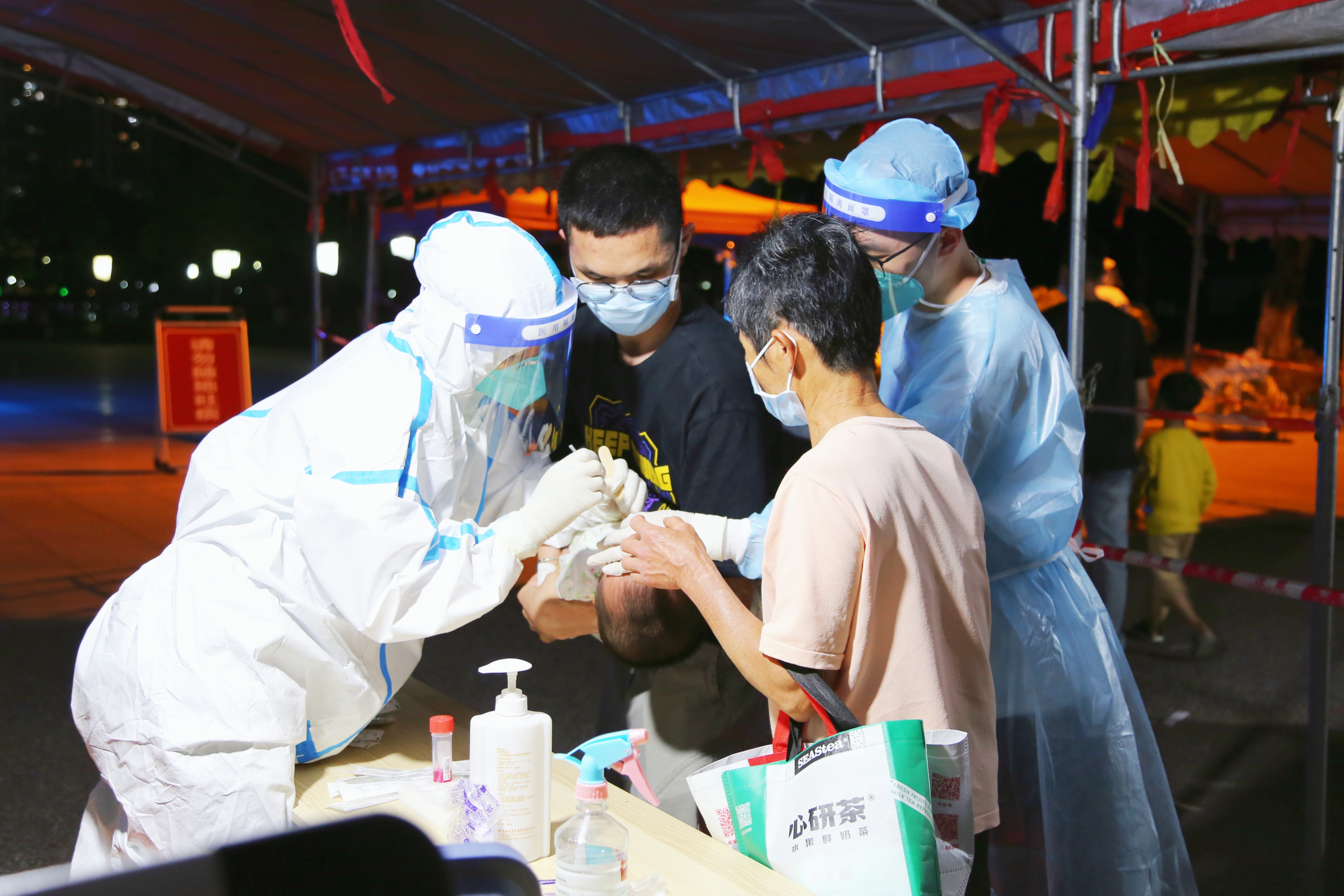 西江产业新城党员干部主动上前帮忙，协助年龄较小的孩子进行核酸采样。.jpeg